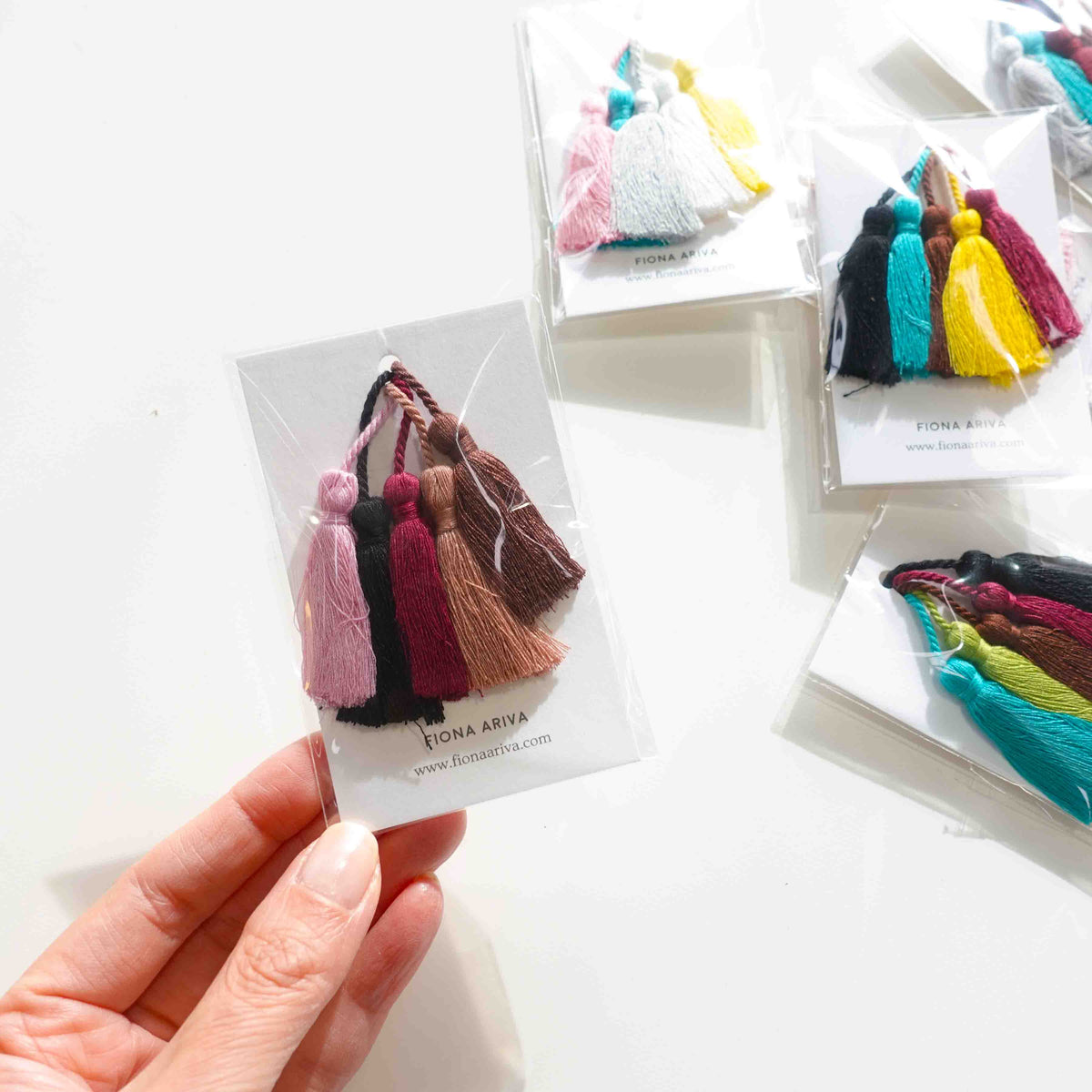 Hand holding a mixed cotton tassel with assorted colour tassels