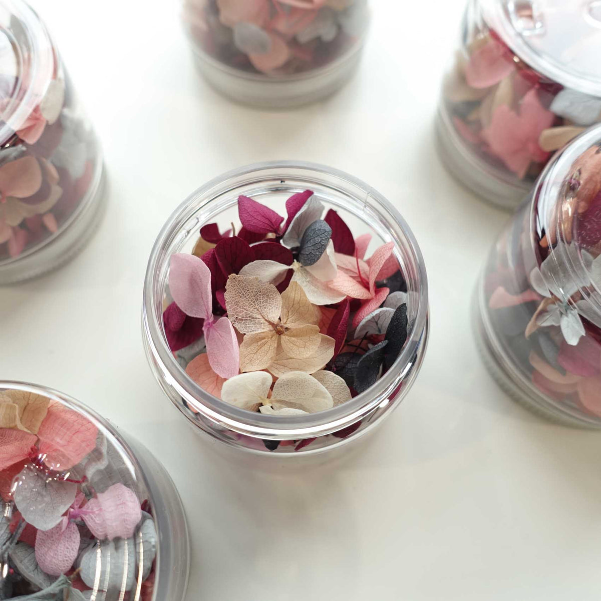Jars of dried hydrangea petals in mixed pink and berry tones