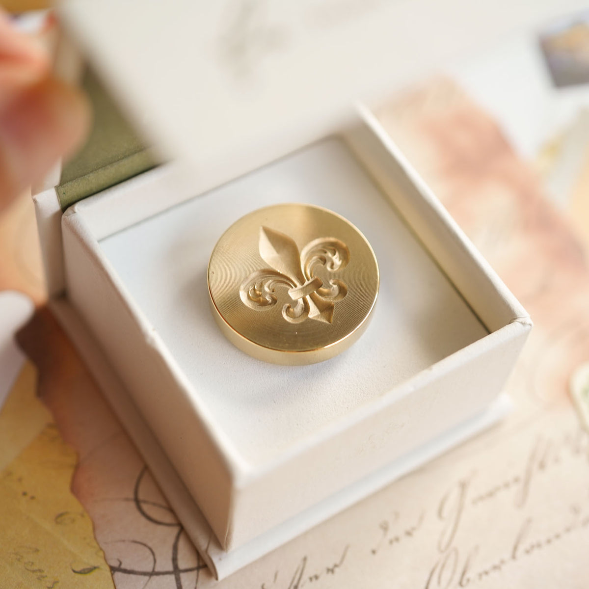 Gold fleur de lis 3D wax seal stamp head sitting in an open white gift box. Fiona Ariva Australia