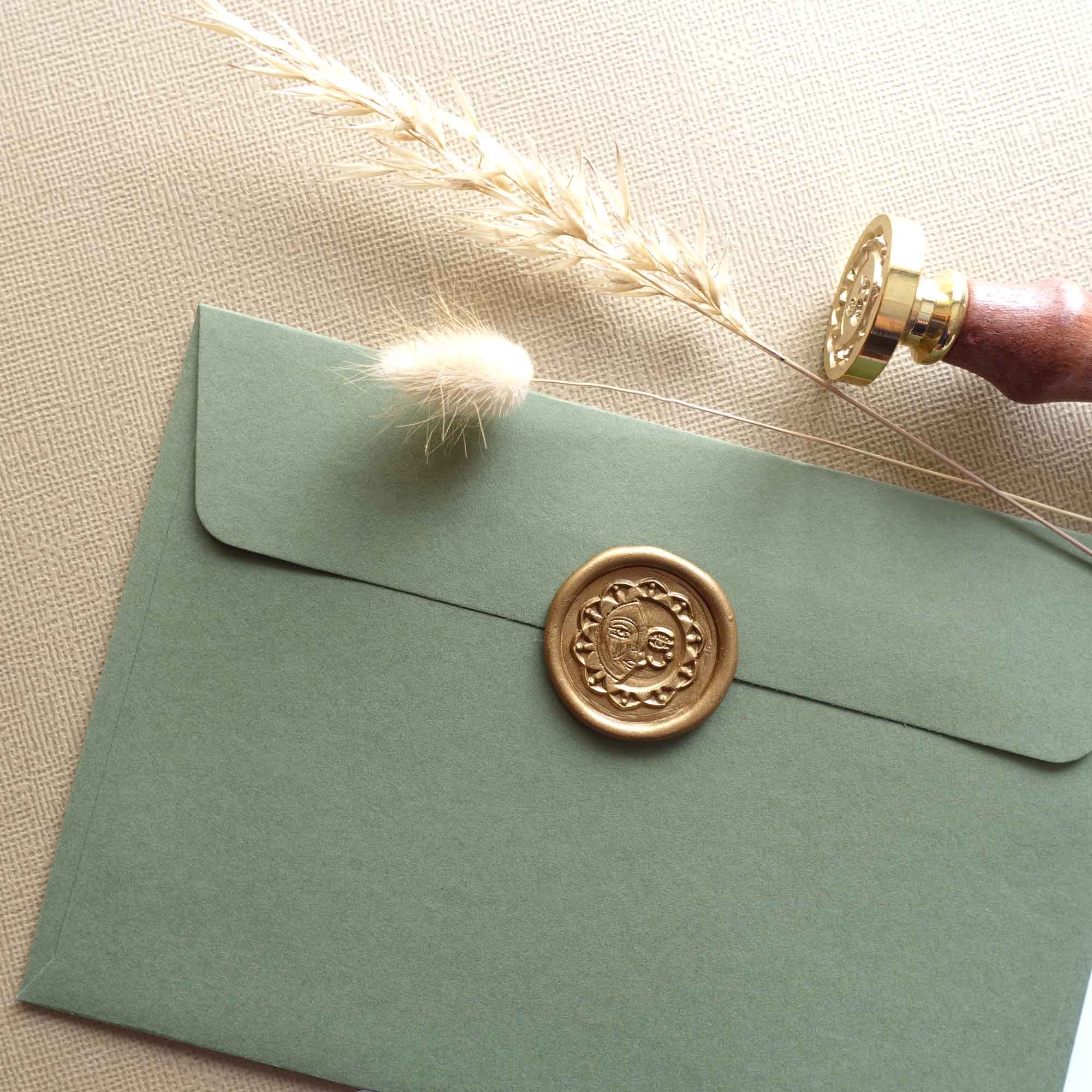 Antique gold half sun and crescent moon wax seal stamp on olive green envelope