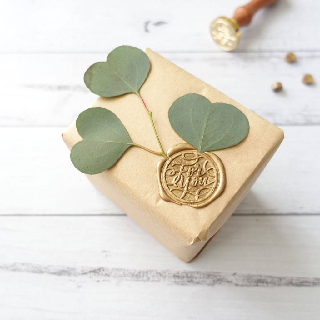 Gift wrapped with eucalyptus leaves and a gold wax seal