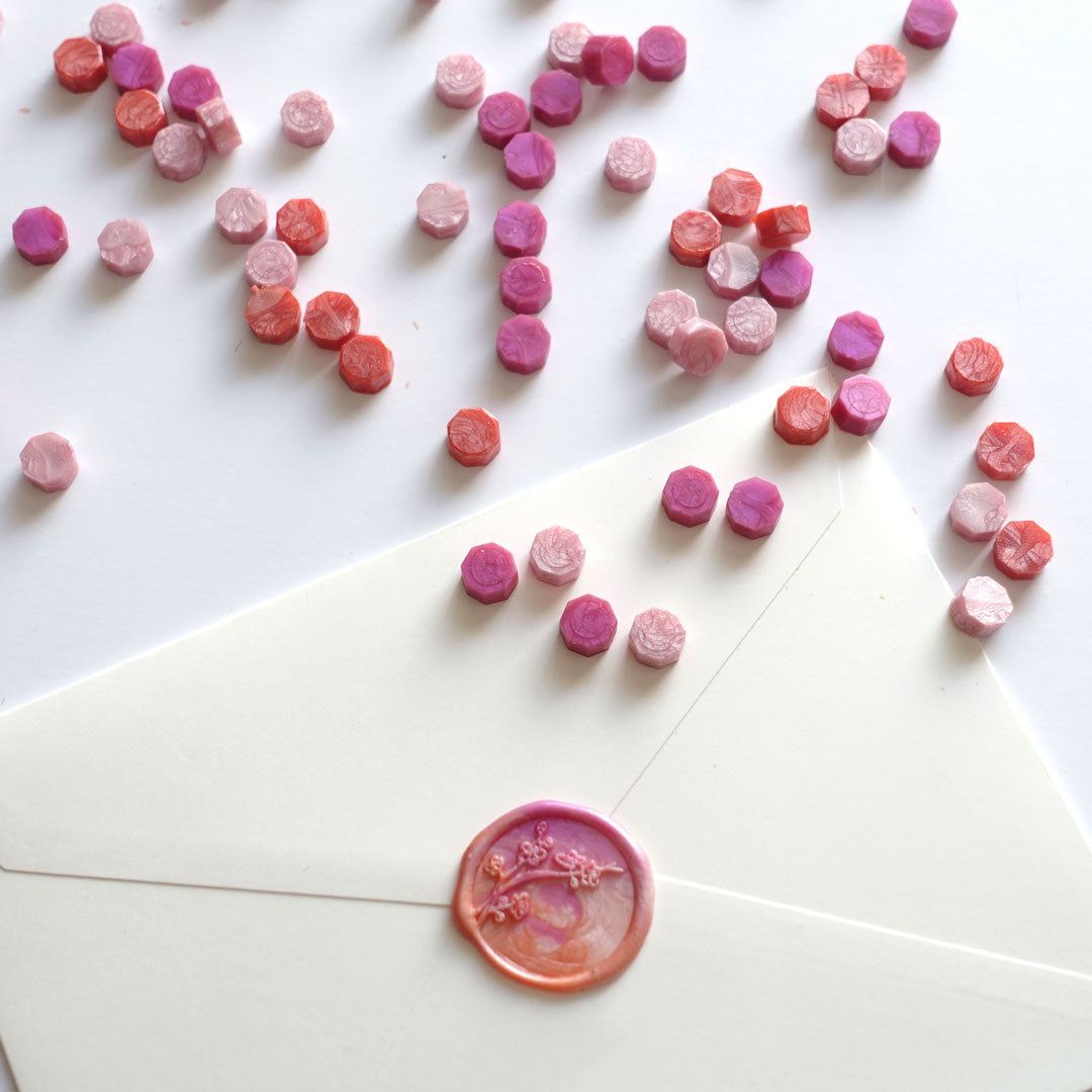 Mixed pink wax beads pellets granules with cherry blossom wax seal on white envelope