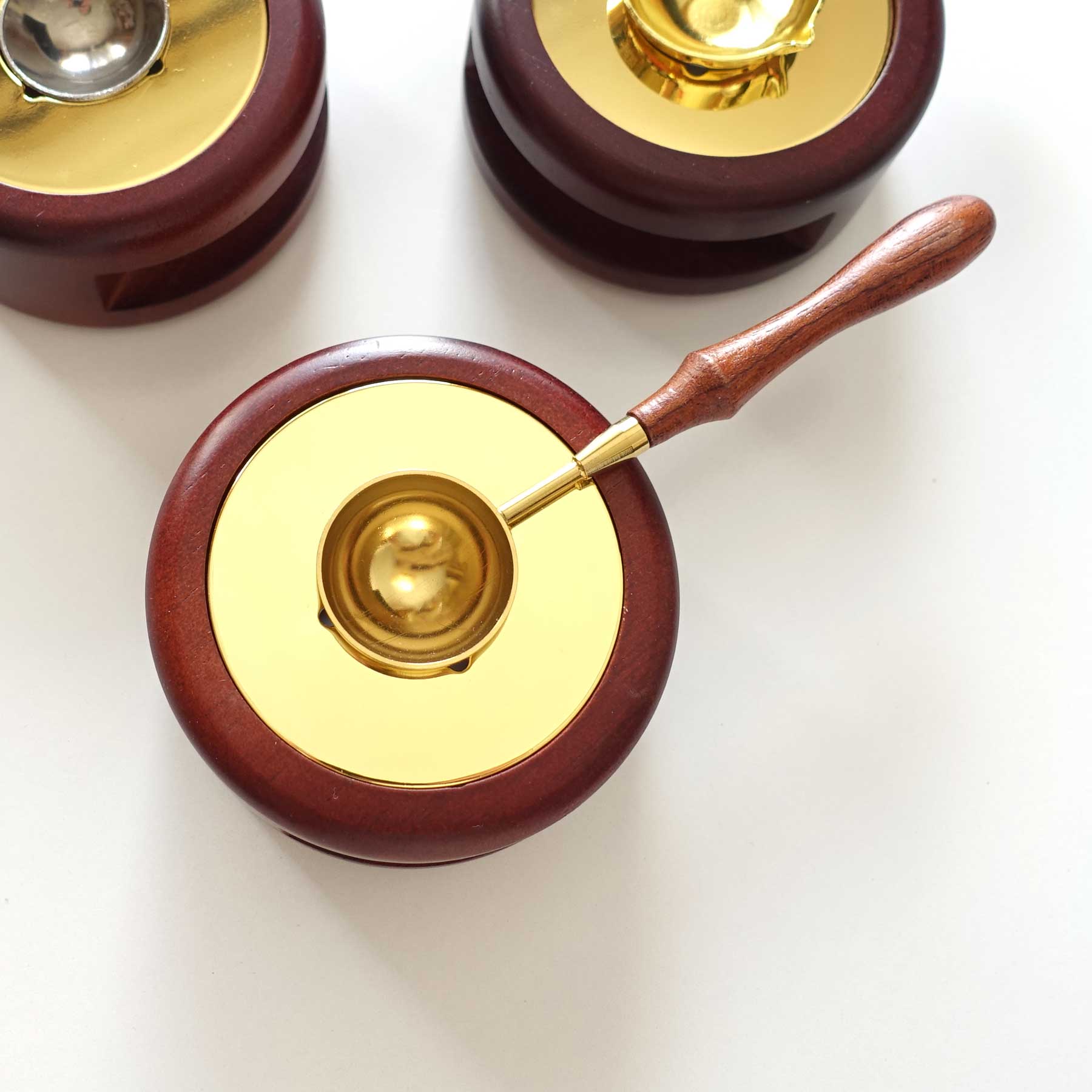 Golden medium handle wax melting spoon on spoon holder 