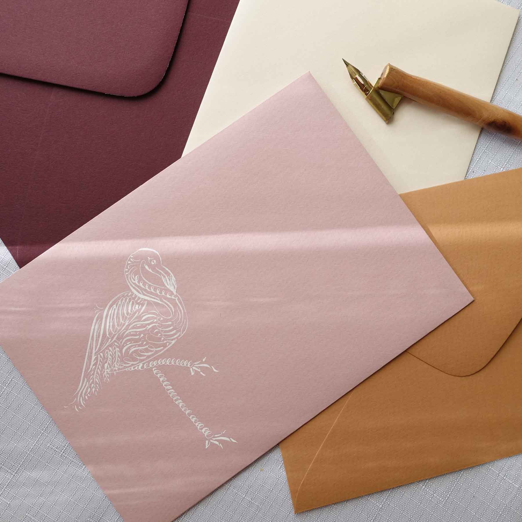 Flamingo animal calligraphy flourishing on pink and terracotta envelope