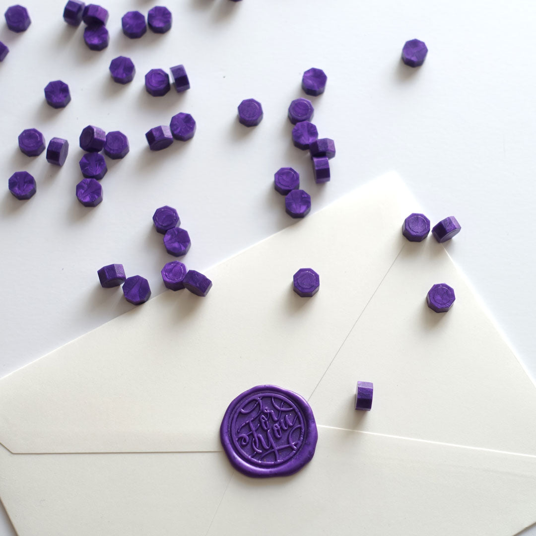 Purple wax beads pellets granules with for you wax seal on white envelope