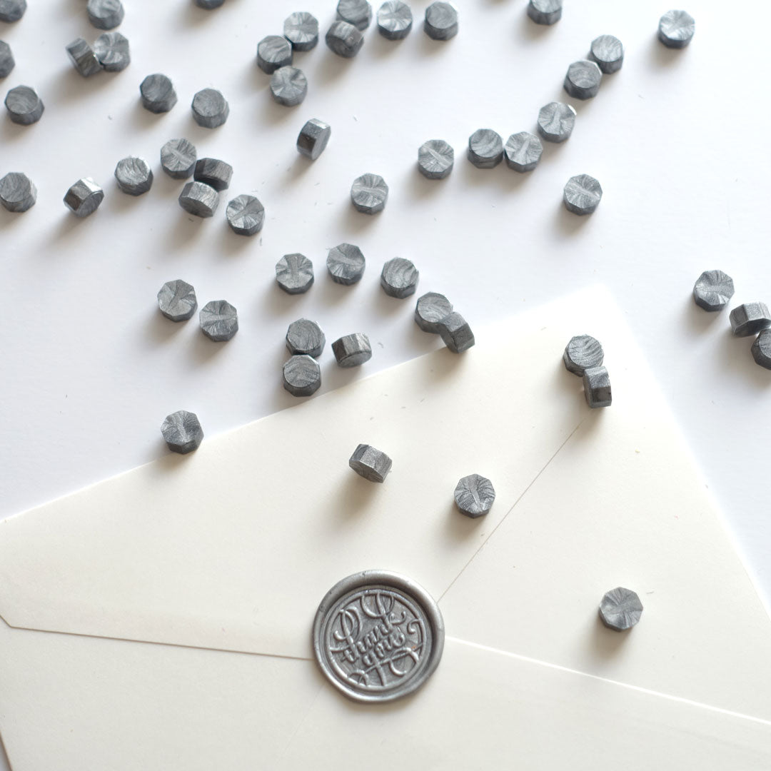 Silver wax beads pellets granules with thank you wax seal on white envelope